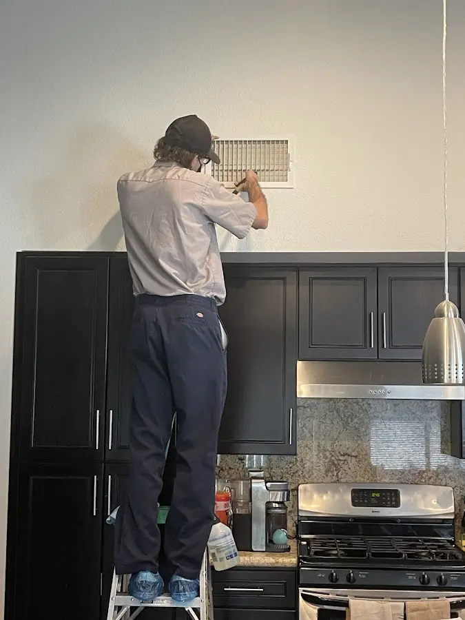 Technician inspecting an air vent during HVAC service in St. Augustine